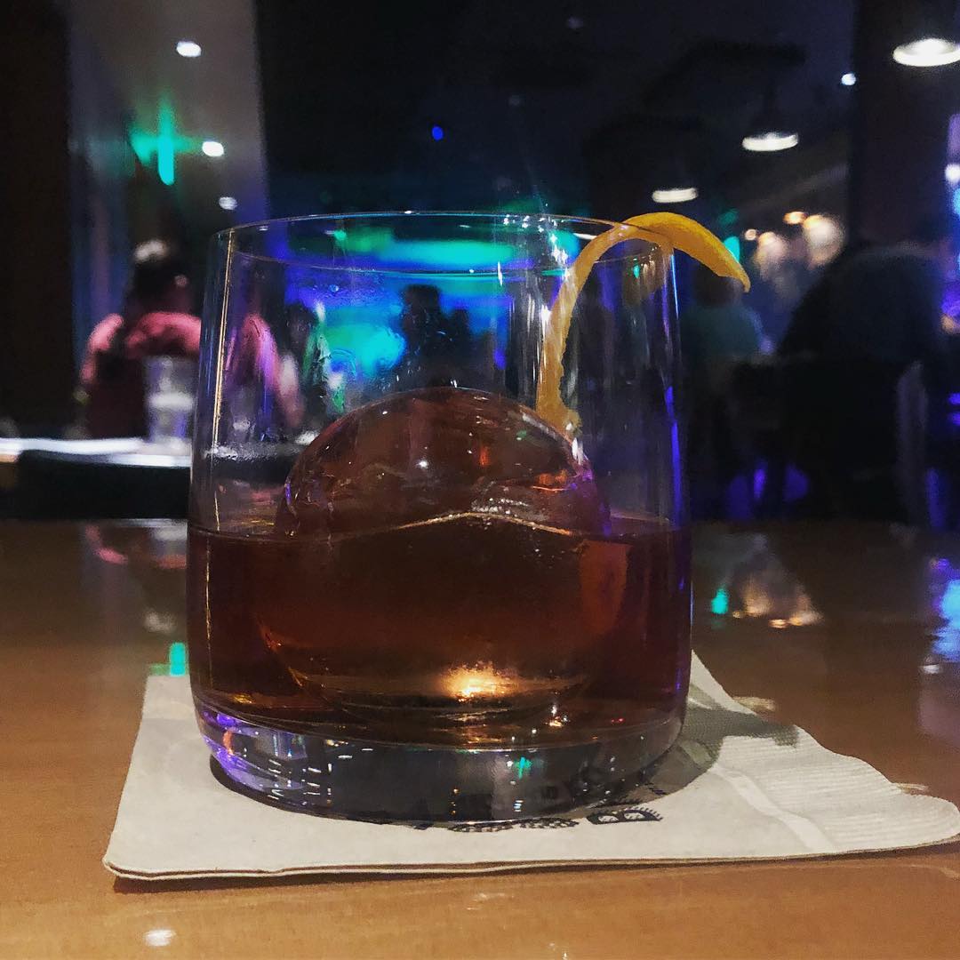 A glass of whiskey with an ice ball
