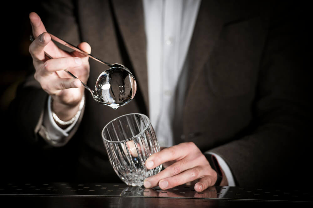 Man placing a clear ice ball in a glass